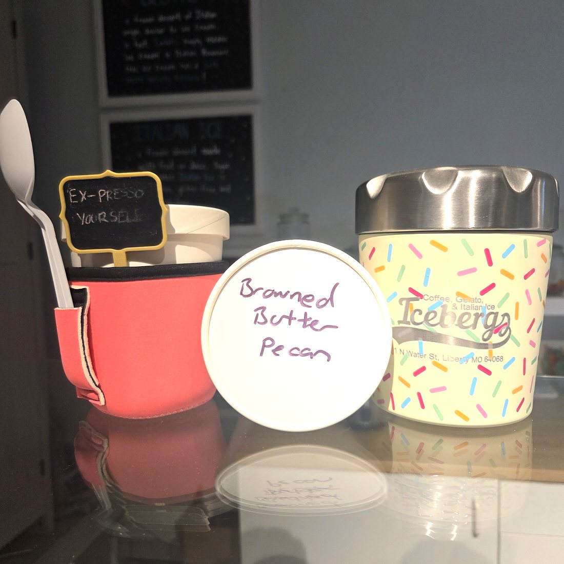 Two Icebergs pints on the counter, one in a sprinkle-printed cup, the other with Browned Butter Pecan written on the lid in marker.